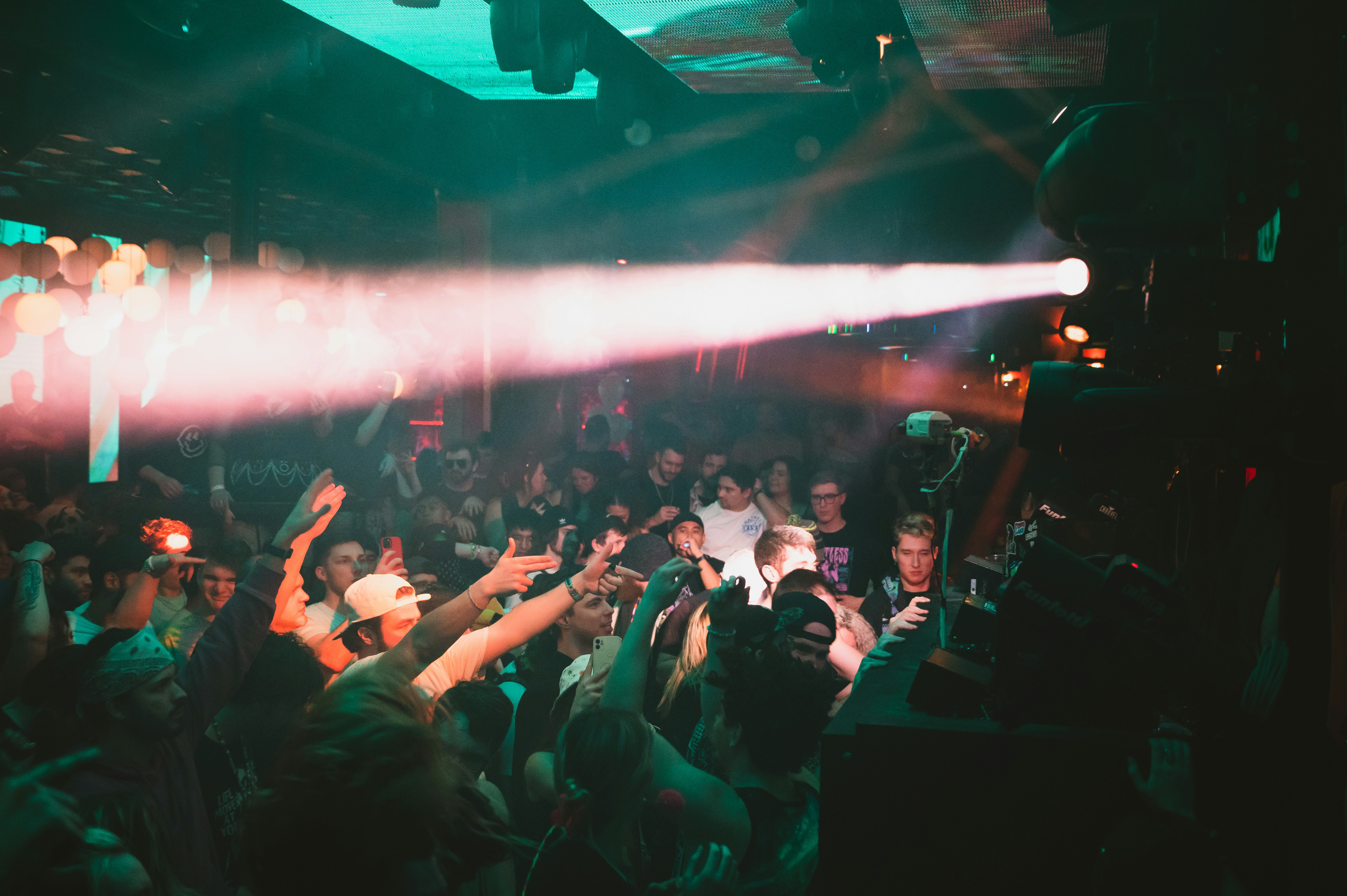 crowd of people raising their hands up in a small, dimly lit area