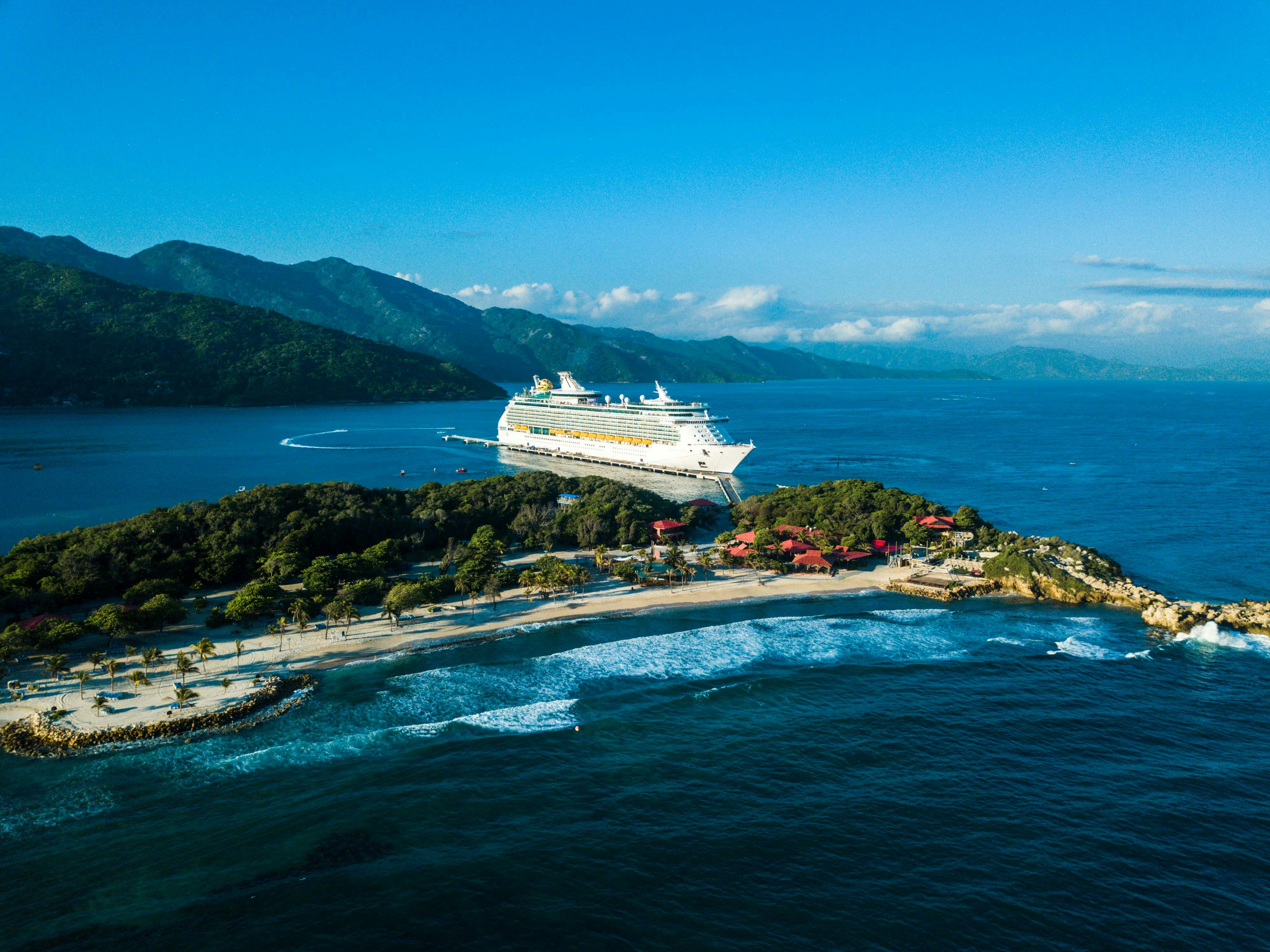 cruise ship arriving to an island with greenery and beaches