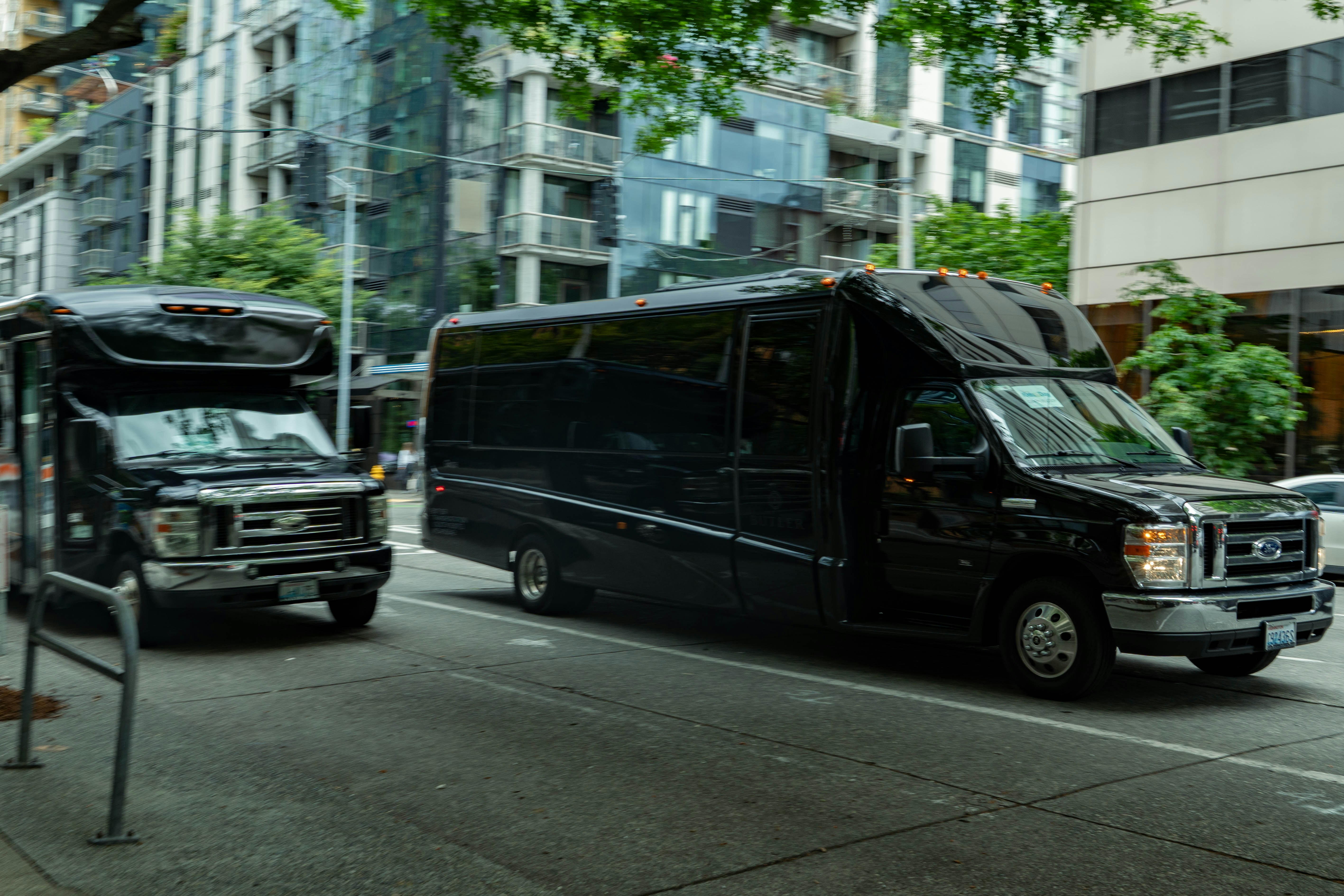 two shuttle cars driving down a road with white buildings around them